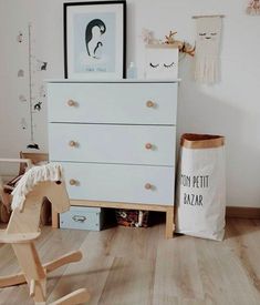 a wooden rocking horse next to a white chest of drawers in a child's room