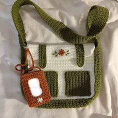 a crocheted purse with an orange and white tag attached to the front, sitting on a bed