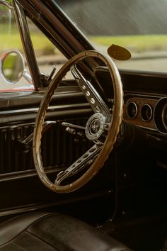 the interior of an old car with wood trim and steering wheel, showing the dashboard