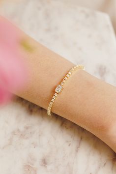 Meet your new favorite accessory: the Amelia Brilliant Cut Tennis Bracelet! We love how it effortlessly adds sparkle to your everyday look, whether you're dressing up for a date night or just want to feel a bit more glam. With its row of dazzling stones and eye-catching emerald cut center, all set in delicate 14k gold plating, this bracelet makes every outfit feel a little more special. The perfect blend of chic and sophisticated, the Amelia Bracelet lets you shine in your own unique way.BRACELE Glamorous Adjustable Bracelet As Gift, Sparkling Adjustable Tennis Bracelet For Party, Glamorous Cubic Zirconia Crystal Bracelet Gift, Glamorous Diamond Accented Bracelets As Gift, Glamorous Bracelets With Diamond Accents As Gift, Glamorous Diamond Accents Bracelet For Gift, Glamorous Adjustable Sparkling Bracelets, Bridal Jewelry Collection, Pearl Collection