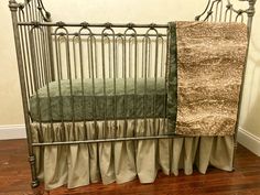 a baby crib with a green and brown blanket on it's side, next to a wooden floor