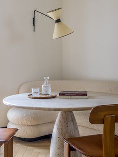 a table and chairs in a room with a lamp on the wall above it, next to a couch