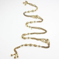 "Vintage Sarah Coventry Multi Strand Gold Tone Chain and Bead Station Lariat Necklace or Belt. This wonderful mod piece dates from the 1960s and would be perfect as a lariat necklace or a belt. Three strands of curb chain are punctuated with smooth and textured beads of various shapes. The necklace is 36 inches long and in Good vintage condition with no damage noted. ERA: Mid Century, 1960s METAL/MATERIALS: Alloy HALLMARKS/HISTORY: Diamond shaped hang tag reading Sarah Cov. with copyright symbol Gold Beaded Dangle Lariat Necklace, Gold Beaded Lariat Necklace With Dangle, Adjustable Gold Lariat Necklace With Dangling Beads, Metal Beaded Chain Lariat Necklace, Gold Beaded Multi-strand Lariat Necklace, Gold Lariat Necklace With Dangling Beads, Beaded Chain Lariat Necklace, Gold Bohemian Lariat Necklace With Dangling Beads, Bohemian Gold Lariat Necklace With Dangling Beads