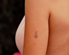 a woman's arm with a small tattoo on the left side of her shoulder