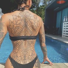 a woman with tattoos on her back standing next to a pool