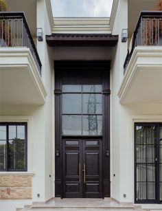 the front entrance to a two story house with black doors and windows on both sides