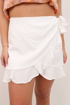 Elevate your outfit with our Wrap Ruffle Skort! Featuring a stylish faux ruffle wrap design, this skort offers a flattering fit and comes with built-in shorts for added comfort. Complete with side ties, this playful skort is perfect for any occasion. Upgrade your wardrobe today and feel confident in your style! Wrap Front Ruffle Skort Side tie Built in shorts Back zipper Katie is 5'4" size 25 wearing a small Casual White Ruffled Skort, White Ruffled Flowy Skort, White Flowy Ruffled Skort, Fitted Ruffle Hem Flirty Skort, White Ruffle Hem Skort, Ruffle Skort, Elevate Your Outfit, Short Leggings, Ruffle Skirt