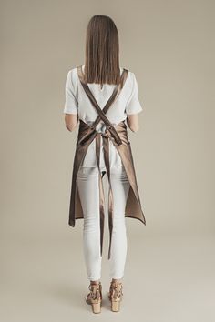 the back view of a woman wearing white jeans and a brown vest