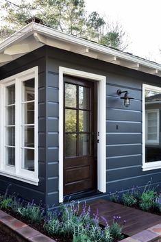 a small gray house with white trim and windows