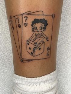 a tattoo on the leg of a person with a playing card in front of them