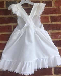 "We used this over a long sleeved red dress(not included).This is a beautiful white pinafore Swiss dot made in USA-in the 80s-no issues/smoke free environment-labeled sz 6- waist elasticized back 11\"-12\"/length (top to bottom) 21 1/2\"/petit lace trim on ruffle sleeve caps and bottom ruffle-no issues(37)" White Sundress Suspender Dress With Ruffles, Fitted Sleeveless Pinafore Dress With Ruffles, White Lace Trim Dress For Picnic, Cute Ruffled Pinafore Dress For Summer, White Swiss Dot Cotton Dress, Fitted Cotton Pinafore Dress With Ruffles, Cute Sleeveless Pinafore Dress With Ruffles, Cotton Lace Trim Dress For Picnic, Cute White Suspender Dress With Ruffles