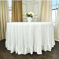 a table with a white cloth on it and flowers in a vase at the top