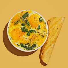 an egg in a bowl next to a piece of bread