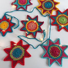 crocheted star ornaments are arranged on a white surface with string lights attached to them