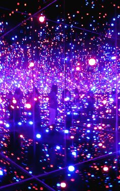 several people are standing in front of an array of colorful lights and balls that appear to be floating