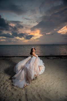 a woman in a white dress on the beach at sunset with her arms around her body