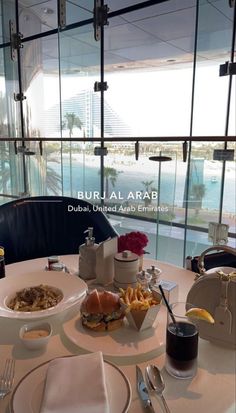 a table with food and drinks on it in front of a large window overlooking the water