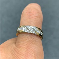 a person's hand with a gold and white ring on top of their finger