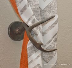 an old pair of scissors hangs on the curtain with orange and white striped fabric behind it