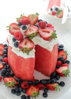 a watermelon cake with strawberries and blueberries on the top is cut in half