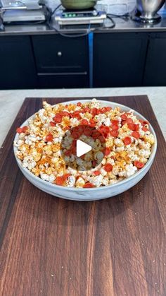 a bowl filled with popcorn on top of a wooden cutting board