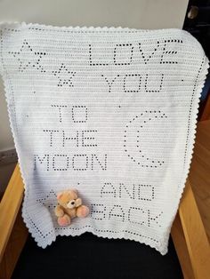 a crocheted baby blanket with a teddy bear on it and the words love you to the moon written in cursive letters