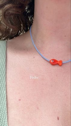 a woman wearing a necklace with an orange fish charm on it's neck and the word fishy written across her chest