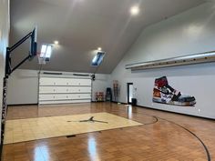 an indoor basketball court with hard wood flooring and white painted walls is seen in this image