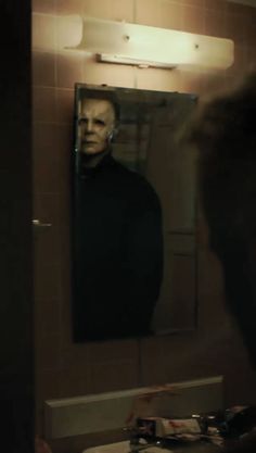 a man standing in front of a bathroom mirror