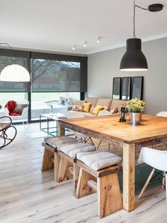 a large wooden table sitting in the middle of a living room next to a window