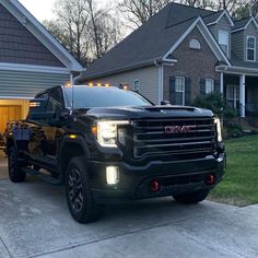 a black truck parked in front of a house with lights on it's hood