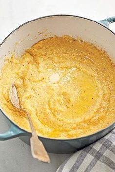 a blue pot filled with batter on top of a white tablecloth next to a wooden spoon