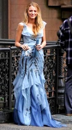 a woman in a blue dress is walking down the street