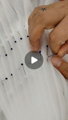 a person is working with pins on a piece of white material that has been stitched together