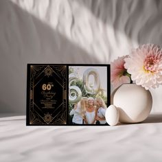 a vase filled with pink flowers next to an 80th birthday card on a bed