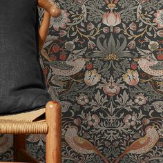 a wooden chair sitting in front of a wallpaper with birds and flowers on it