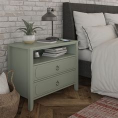 a bed room with a neatly made bed and a night stand on top of it