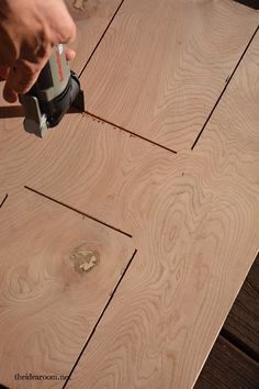 a person using a drill to glue wood on a piece of plywood planks