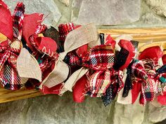 red, white and black hair bows sitting on top of a wooden bench next to a stone wall