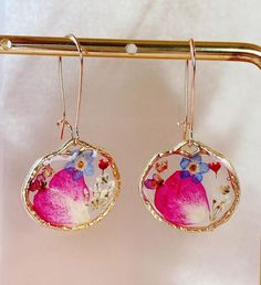 pair of pink and blue flowered earrings hanging from gold earwires on white background