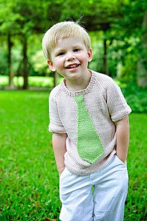 a little boy standing in the grass wearing a green tie