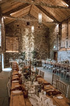 a long table set up with place settings for dinner in a stone walled room, surrounded by wooden tables and chairs