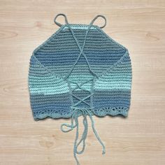 a crocheted blue and green sweater on top of a wooden table with string