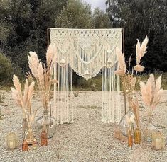 some vases with flowers and plants in them on the ground near a white curtain