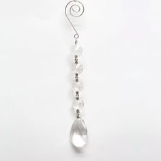 a long crystal beaded necklace hanging from a hook on a white background with silver wire