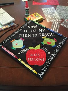 a graduation cap with writing on it sitting on top of a table next to other school supplies