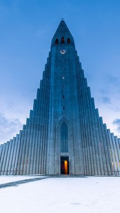 a very tall building with a clock on it's face and an open door