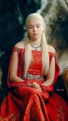 a woman with long blonde hair sitting in a red dress