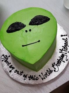 there is a green cake that has been decorated with the face of an alien on it