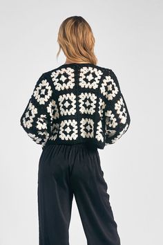 a woman in black and white sweater with flowers on the back, wearing high rise pants